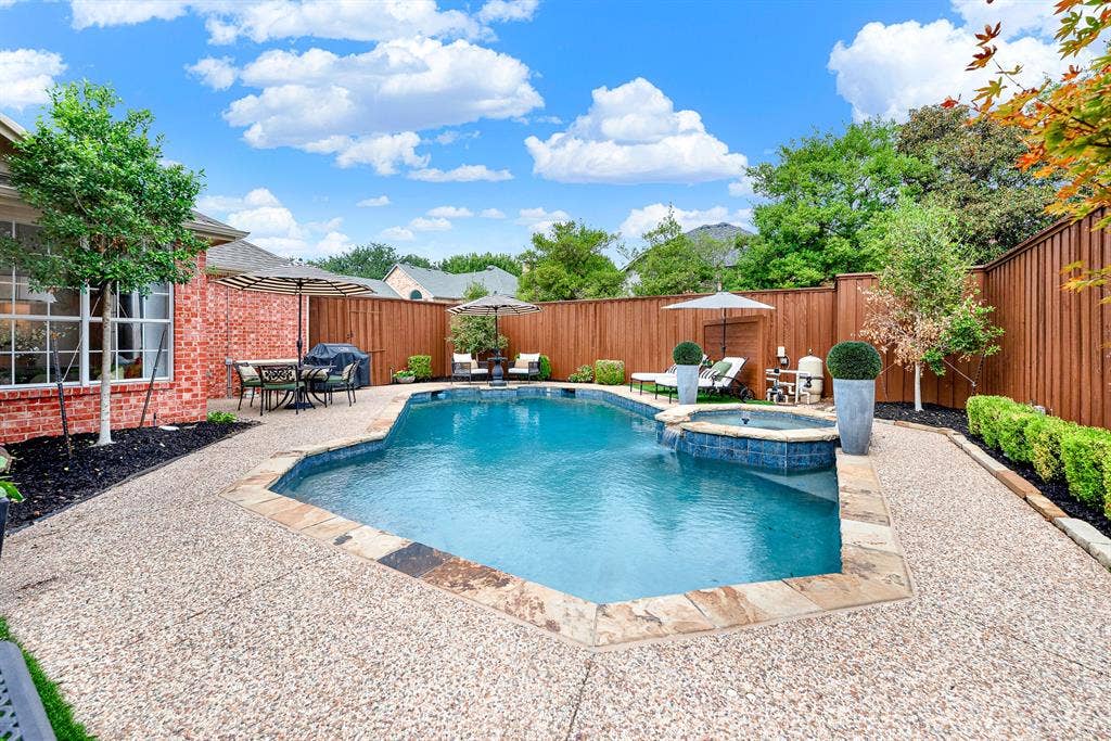 6429 GLENHOLLOW Drive, Plano, TX 75093 Lush artificial turf in the backyard creates a vibrant, low-maintenance green corner tucked against classic red brick. Savor a peaceful morning coffee beneath shade umbrellas in your serene outdoor sanctuary.