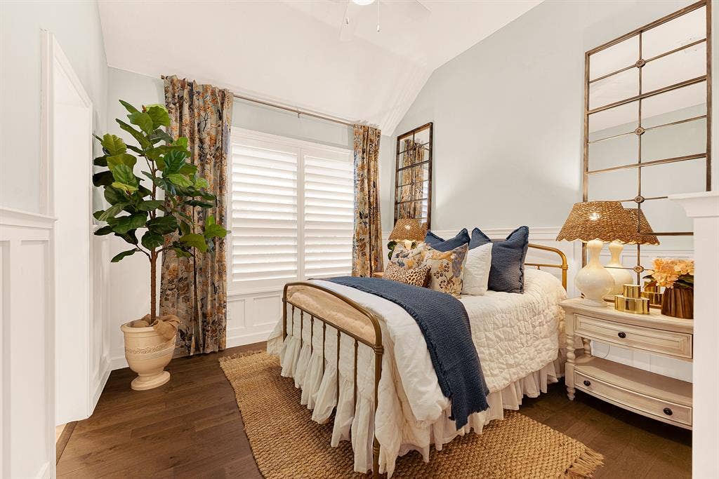 6429 GLENHOLLOW Drive, Plano, TX 75093 Bedroom 2 features beautiful wainscoting and millwork detail that grounds the room under a soaring vaulted ceiling, catching soft daylight through shuttered windows. Welcome overnight guests to a serene haven where hey can instantly unwind and recharge.