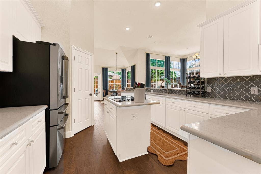 6429 GLENHOLLOW Drive, Plano, TX 75093 A centered cooktop island enhances functional traffic flow beneath high vaulted ceiling lines. Sip a quick afternoon espresso while watching sunlight stream through the adjoining living spaces.