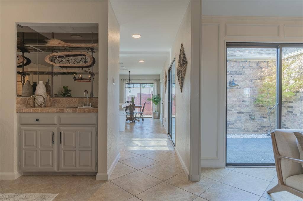 1011 Wimbledon Lane, Plano, TX 75075 Built-in wet bar with a single basin sink, light-colored cabinetry, and mirrored backsplash
