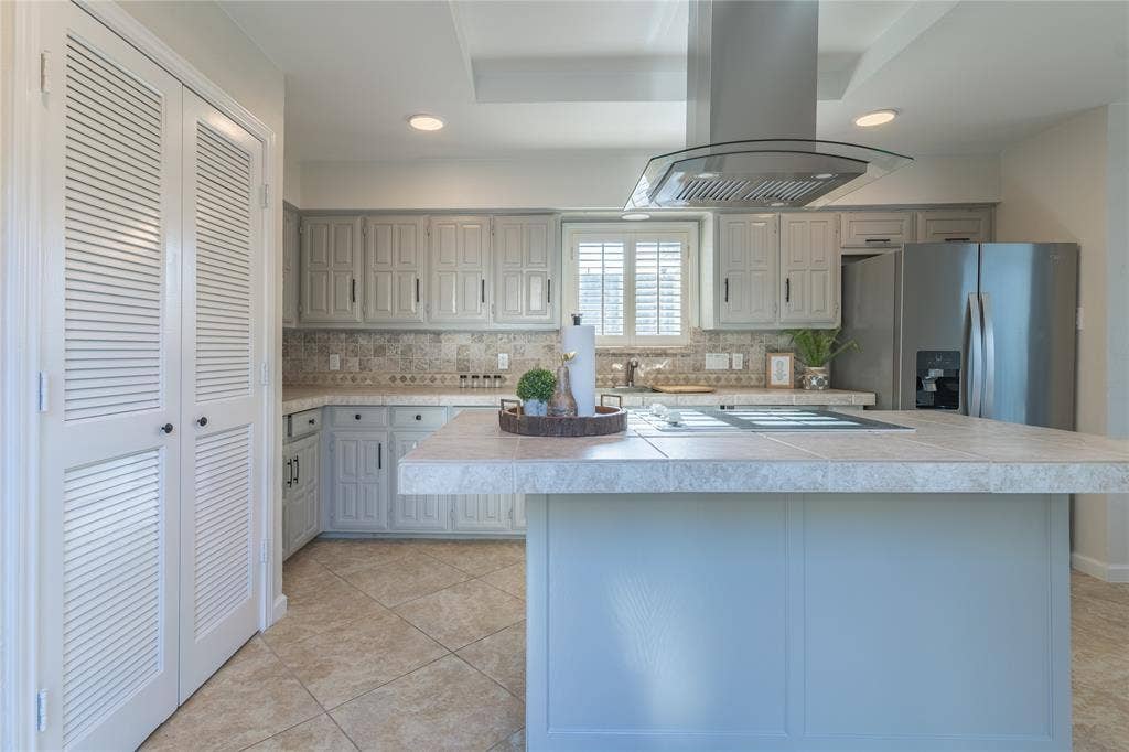 1011 Wimbledon Lane, Plano, TX 75075 Contemporary kitchen featuring a stainless steel range hood, tile flooring, recessed lighting, and louvered bi-fold doors