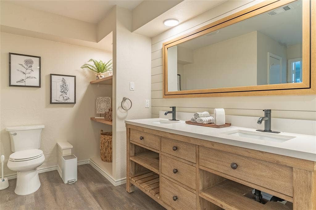 1011 Wimbledon Lane, Plano, TX 75075 Dual vanity with integrated sinks and matte black fixtures, set on a wood-finish cabinet with drawers and open shelving