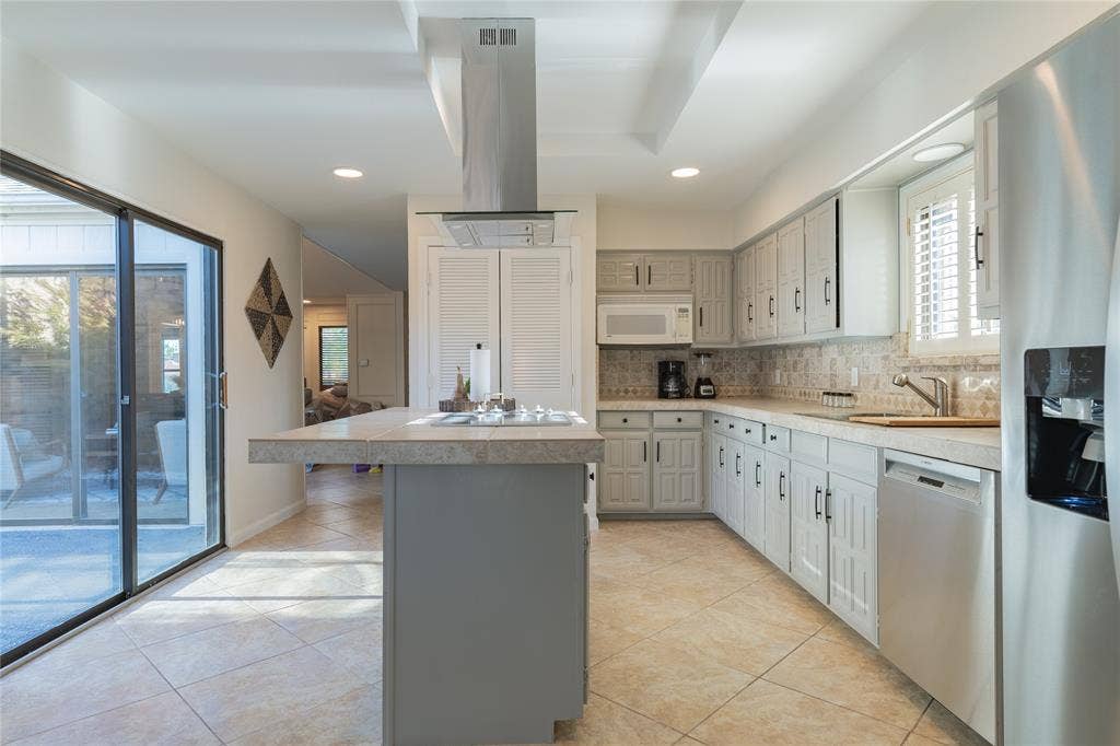 1011 Wimbledon Lane, Plano, TX 75075 Kitchen featuring neutral tile flooring, light-toned cabinetry, light countertops, stainless steel appliances, and a sliding glass door