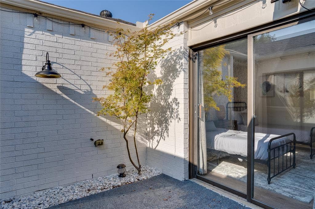 1011 Wimbledon Lane, Plano, TX 75075 White painted brick exterior with a wall-mounted outdoor light fixture
