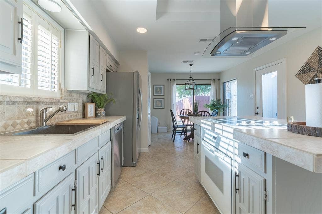 1011 Wimbledon Lane, Plano, TX 75075 Recessed lighting, stainless steel appliances, tile flooring, glass-front cabinetry, and a ceiling-mounted range hood