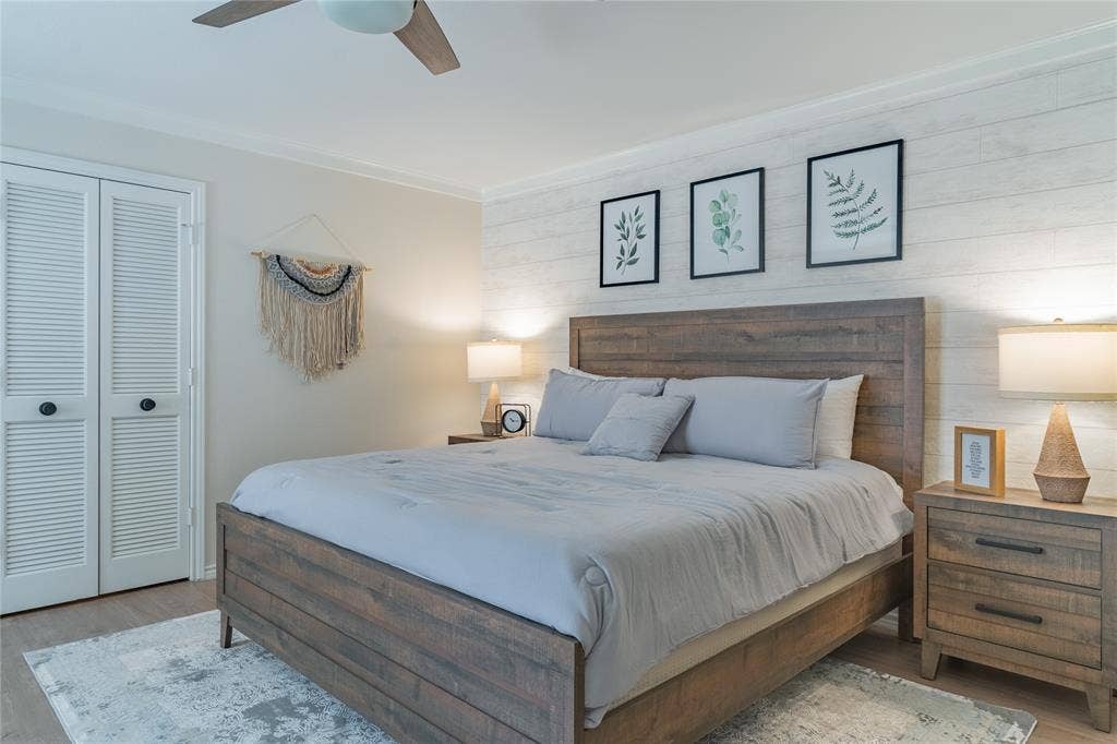 1011 Wimbledon Lane, Plano, TX 75075 Wood-finish flooring, white shiplap accent wall, louvered bi-fold closet doors, ceiling fan with integrated lighting, and crown molding