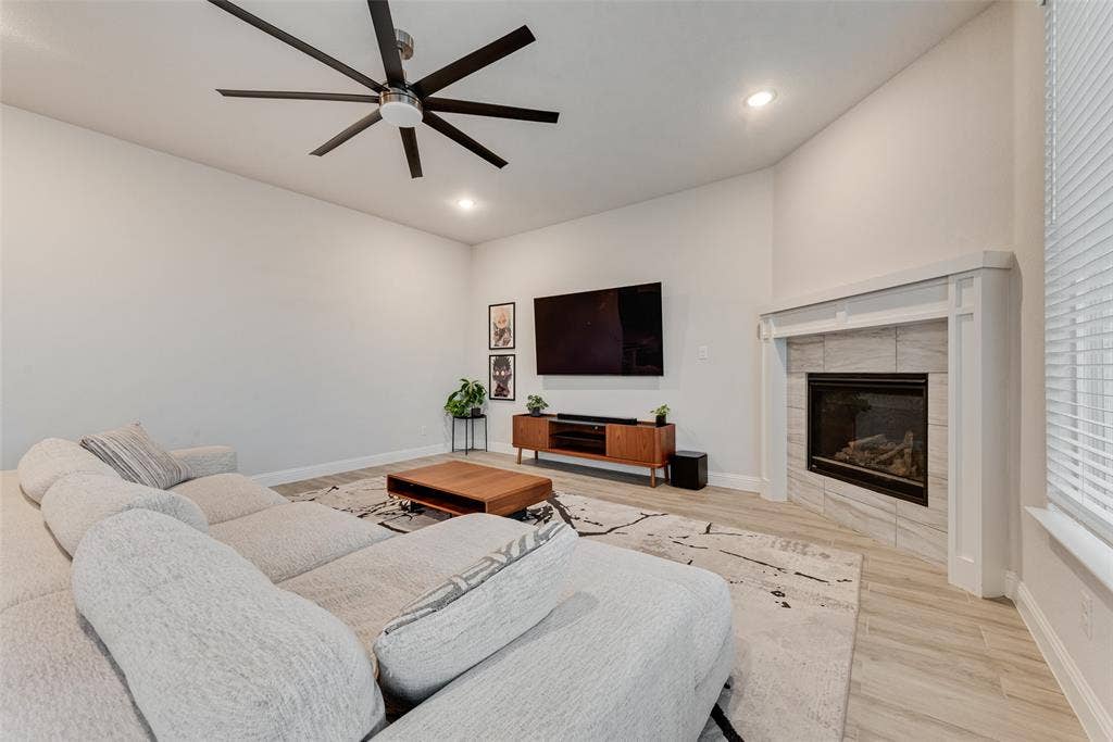 812 Stamford Avenue, Arlington, TX 76002 Vaulted ceiling with a contemporary ceiling fan, recessed lighting, corner fireplace with tile surround, and light wood-finish flooring