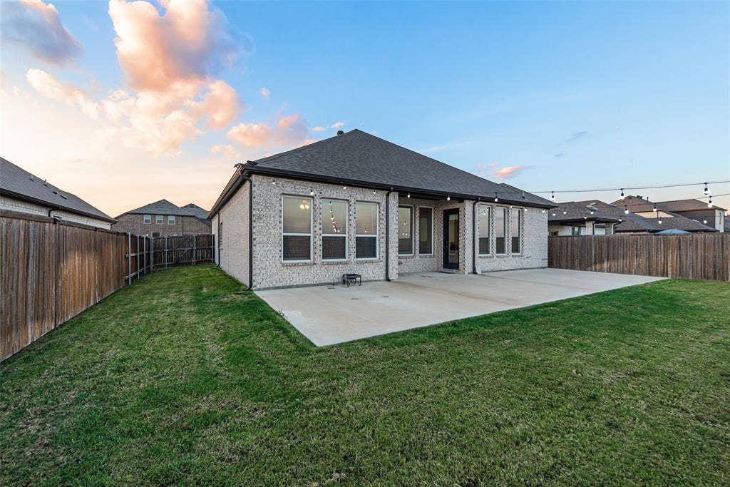 812 Stamford Avenue, Arlington, TX 76002 Expansive backyard featuring a manicured lawn, a large concrete patio, and a brick exterior