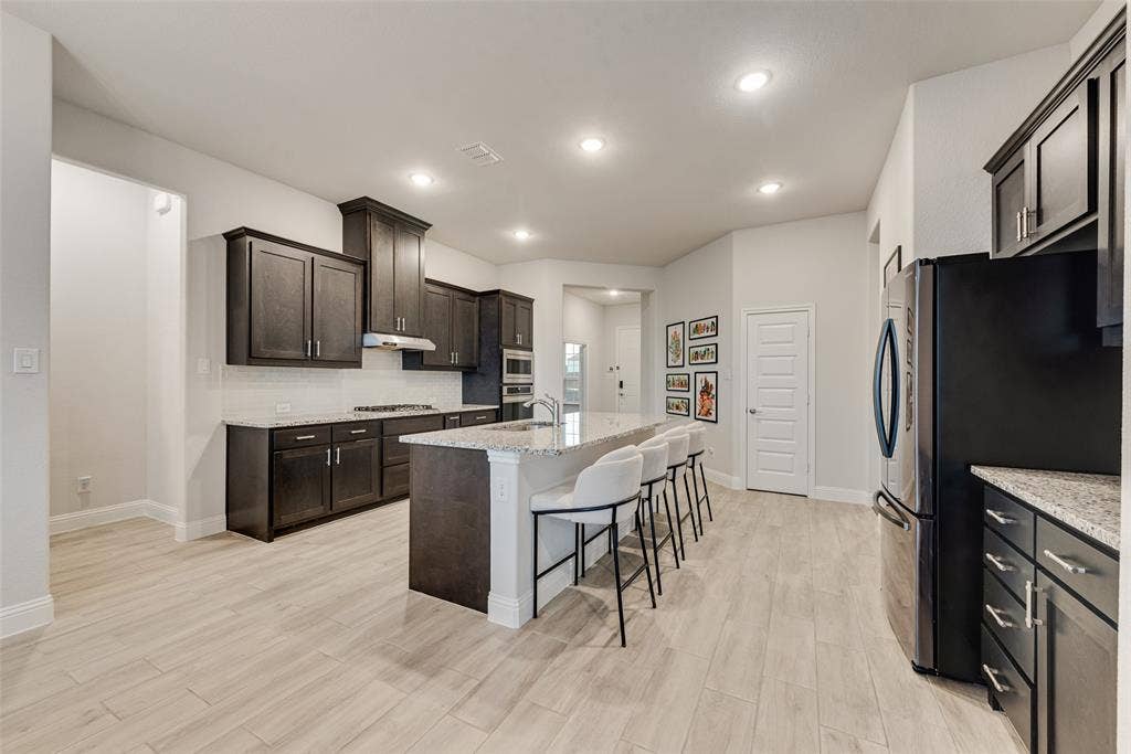 812 Stamford Avenue, Arlington, TX 76002 Spacious kitchen featuring dark wood cabinetry, light-colored countertops, stainless steel appliances, and wood-finish flooring