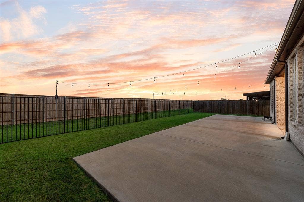 812 Stamford Avenue, Arlington, TX 76002 Expansive concrete patio with a manicured lawn, full privacy fencing, and string lighting