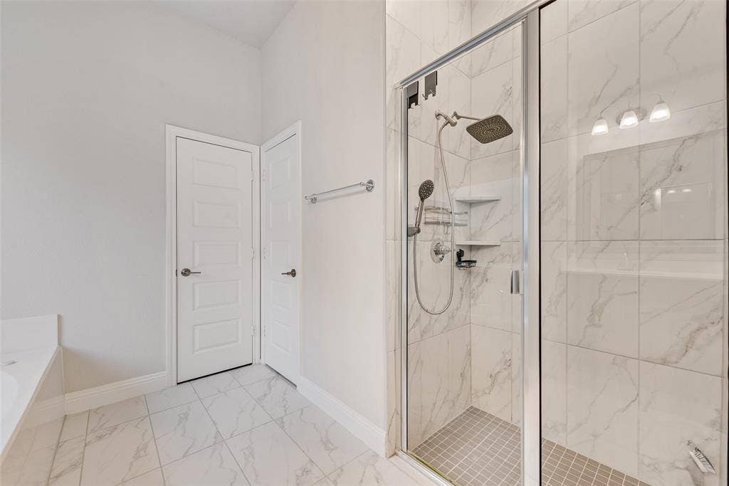 812 Stamford Avenue, Arlington, TX 76002 Glass-enclosed shower with a rainfall showerhead, handheld sprayer, built-in shelving, and a tiled floor
