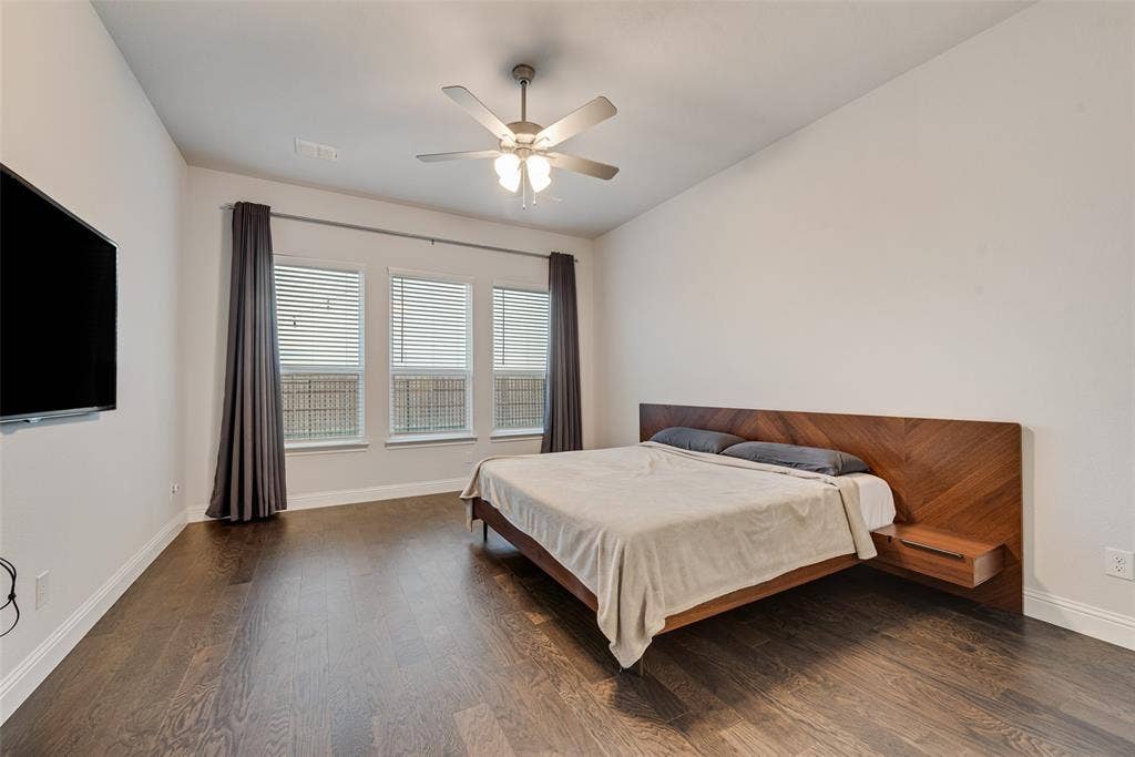 812 Stamford Avenue, Arlington, TX 76002 Dark wood-finish flooring, three large windows, and a ceiling fan with integrated lighting