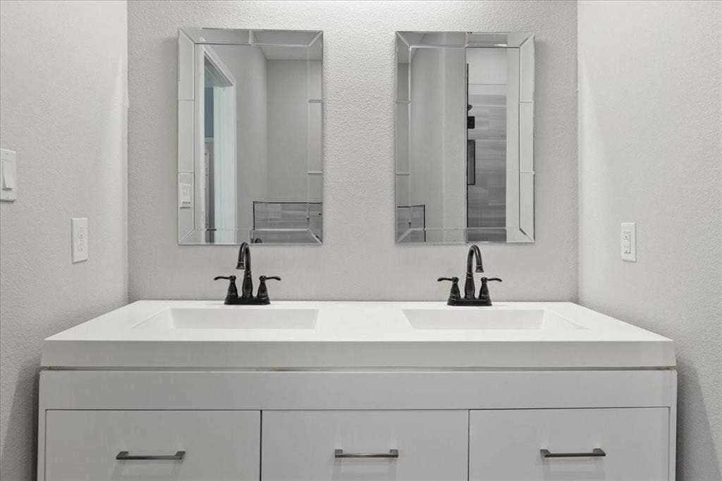 7919 N kiska Street, Dallas, TX 75216 Dual white integrated sinks with dark bronze fixtures set in a white vanity with paneled drawer fronts and dark bronze pulls