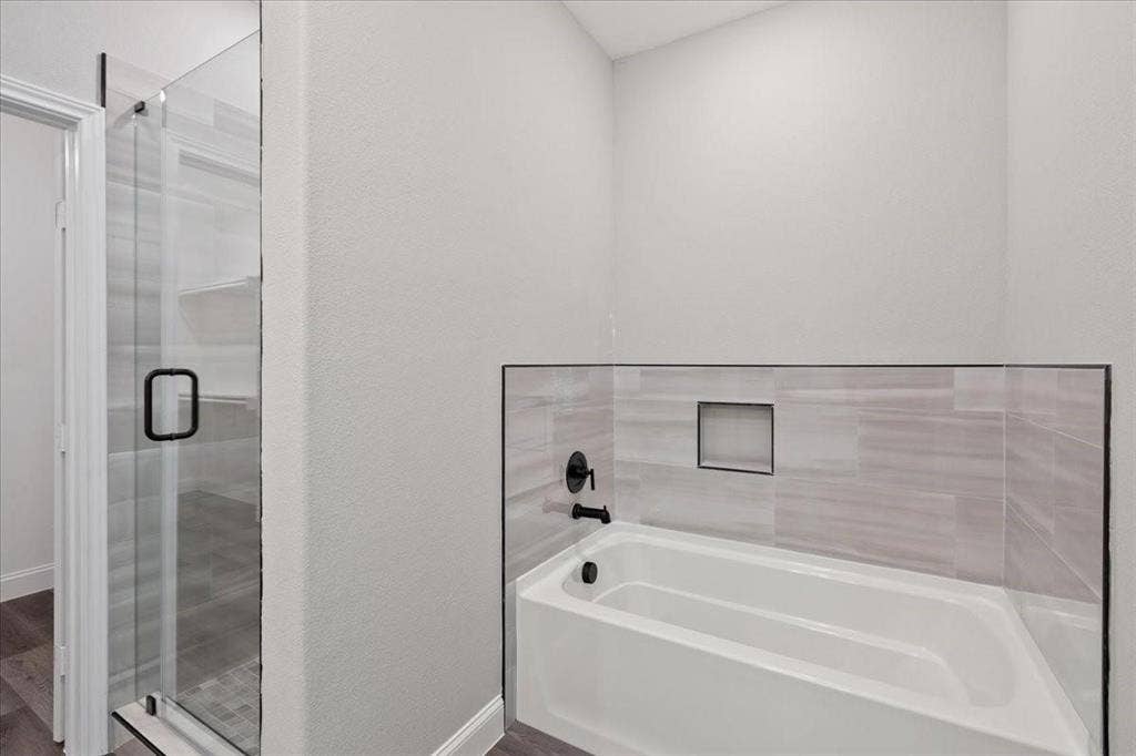 7919 N kiska Street, Dallas, TX 75216 Glass-enclosed shower with matte black hardware, tiled shower floor, built-in bathtub with matte black fixtures, and tiled surround with integrated niche