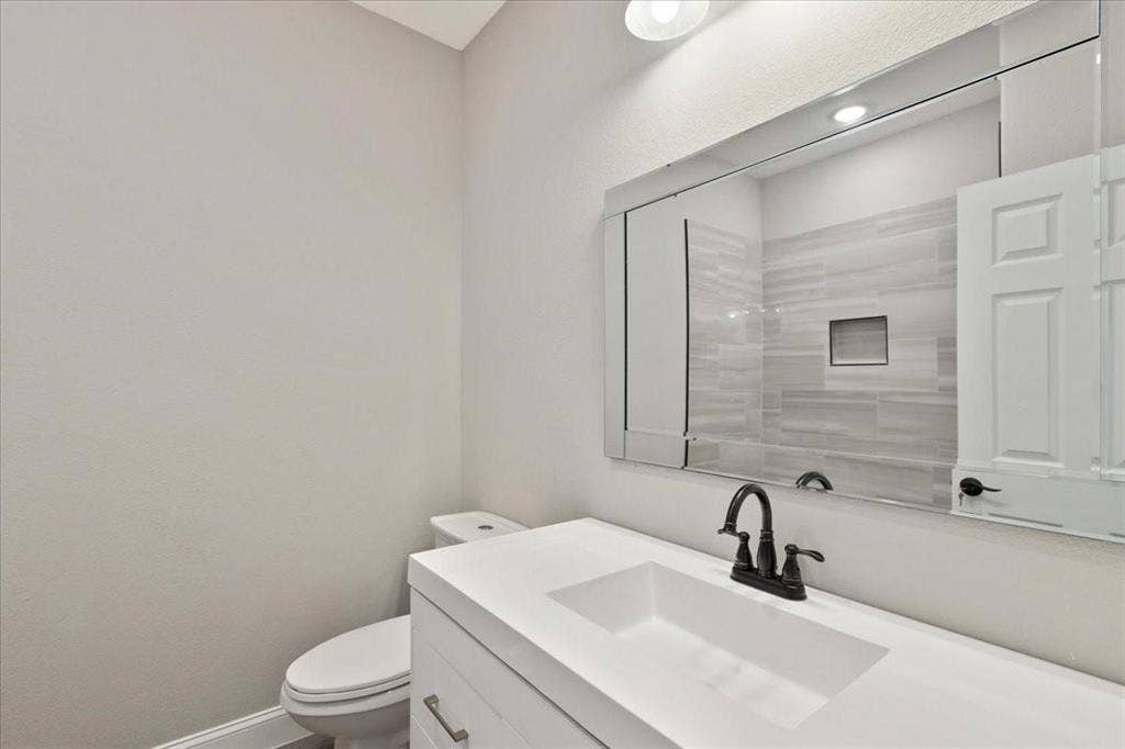 7919 N kiska Street, Dallas, TX 75216 Vanity featuring a rectangular undermount sink, dark bronze-finish faucet, and a large wall-mounted mirror