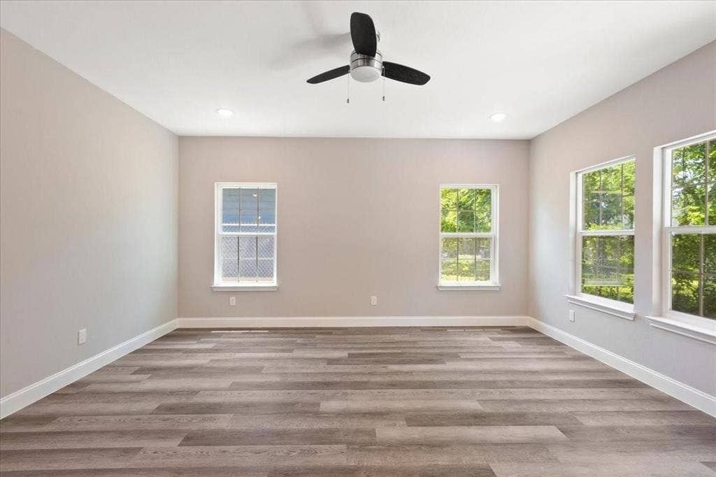 7919 N kiska Street, Dallas, TX 75216 Spacious room featuring wood-finish flooring, multiple windows, a ceiling fan, and recessed lighting