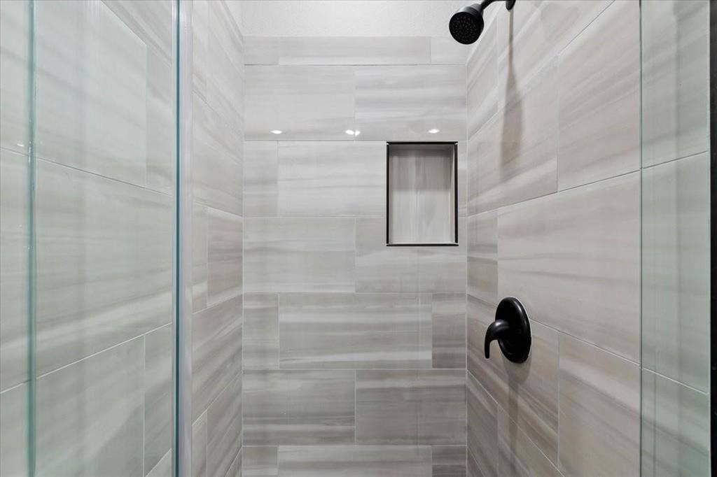 7919 N kiska Street, Dallas, TX 75216 Glass-enclosed shower with horizontally-laid tile, recessed lighting, a built-in niche, and matte black fixtures