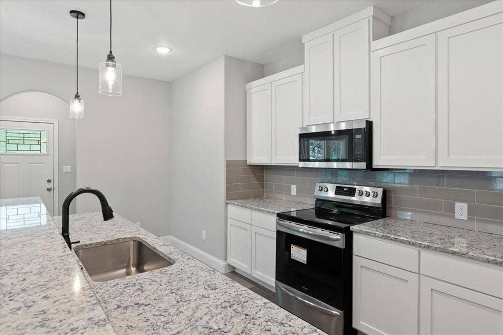 7919 N kiska Street, Dallas, TX 75216 Kitchen featuring white shaker cabinetry, stainless steel appliances, granite countertops, a subway tile backsplash, and pendant lighting