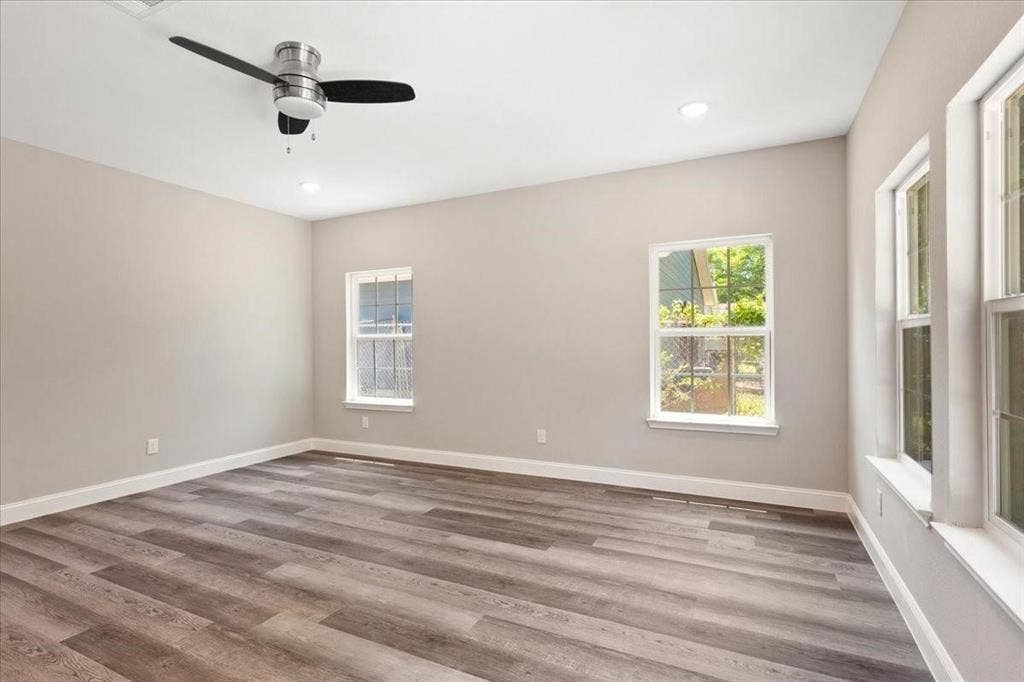 7919 N kiska Street, Dallas, TX 75216 Spacious room featuring wood-finish flooring, light neutral wall paint, a ceiling fan, recessed lighting, and multiple windows