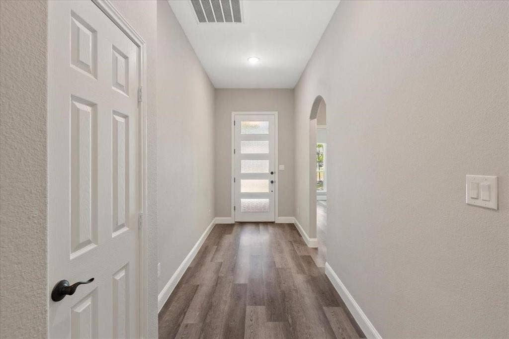7919 N kiska Street, Dallas, TX 75216 Entryway featuring wood-finish flooring, a modern front door with frosted glass panels, and an arched doorway
