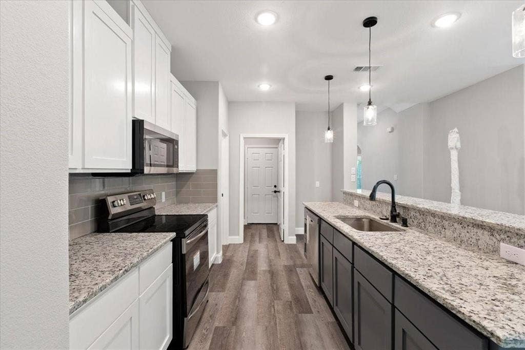 7919 N kiska Street, Dallas, TX 75216 Kitchen featuring granite countertops, wood-finish flooring, stainless steel appliances, white upper cabinetry, and dark lower cabinetry