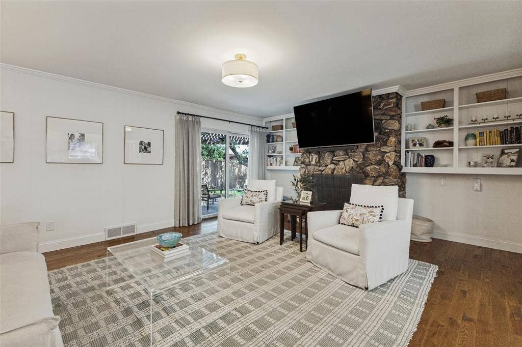 9864 Shoreview Road, Dallas, TX 75238 Stone-clad fireplace with built-in shelving, wood-finish flooring, recessed lighting, and patio access
