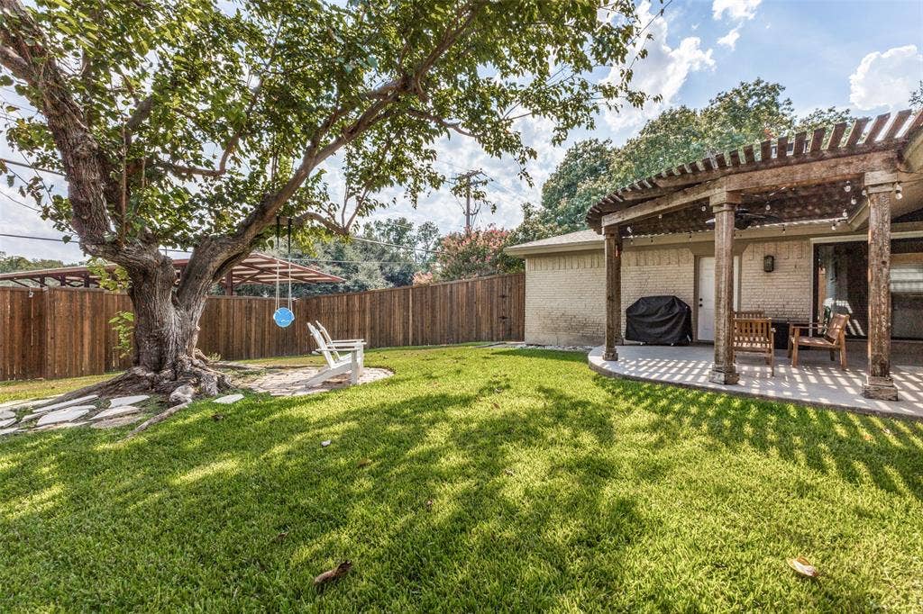 9864 Shoreview Road, Dallas, TX 75238 Expansive backyard featuring a pergola-covered patio, mature shade tree, and wood privacy fencing
