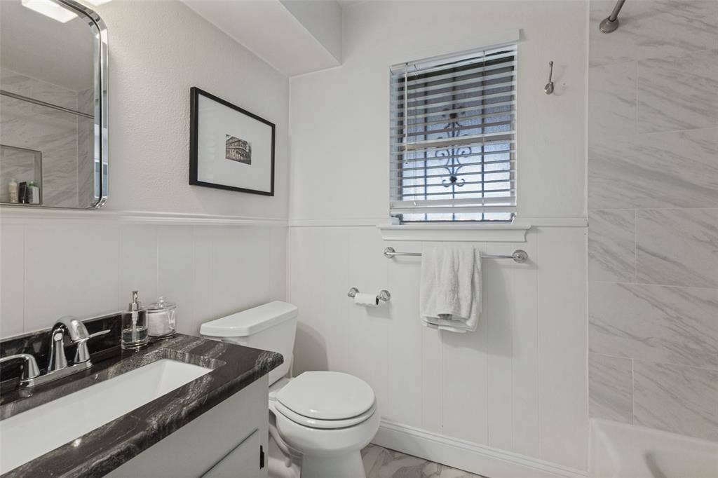 9864 Shoreview Road, Dallas, TX 75238 Vanity with dark countertop and undermount sink, wainscoting, and tiled shower surround