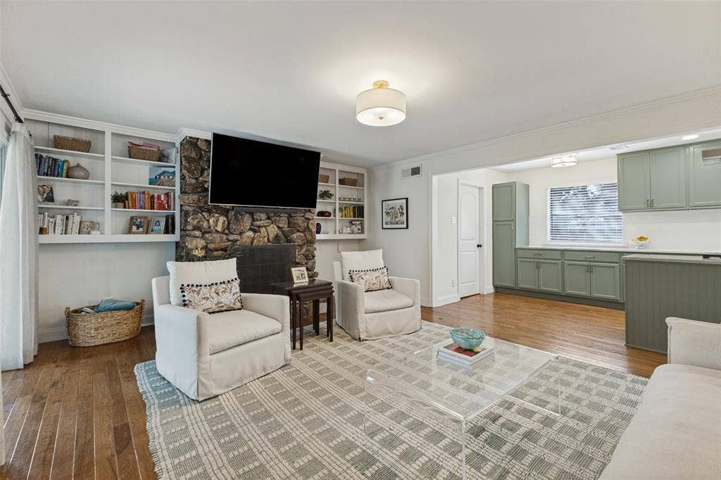 9864 Shoreview Road, Dallas, TX 75238 Stone-clad fireplace with hearth, built-in shelving, wood-finish flooring, and recessed lighting