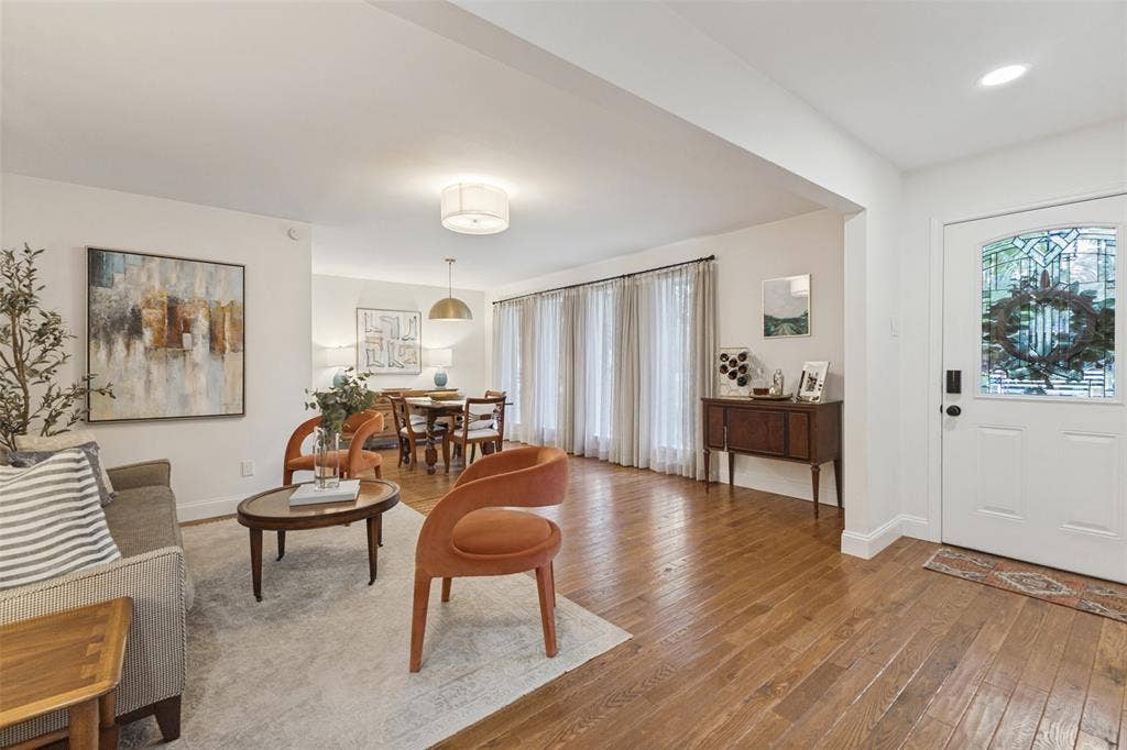 9864 Shoreview Road, Dallas, TX 75238 Light-filled living space with wood-finish flooring, a white paneled entry door with leaded glass, and a dining area