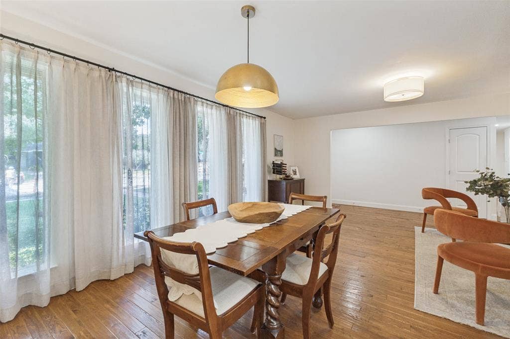9864 Shoreview Road, Dallas, TX 75238 Hardwood flooring, expansive windows with custom drapery, a central pendant light fixture, recessed lighting, and a white interior door