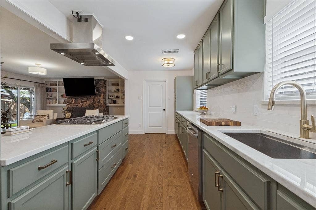 9864 Shoreview Road, Dallas, TX 75238 Kitchen featuring an expansive island with cooktop, stainless steel range hood, full-height backsplash, wood-finish flooring, and recessed lighting