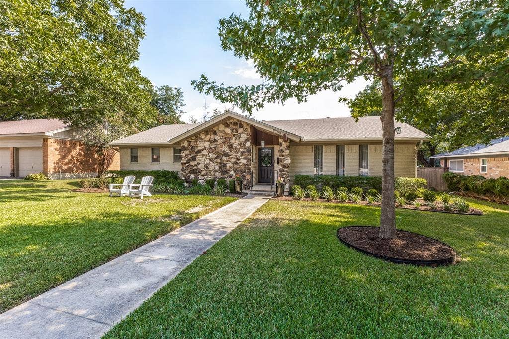 9864 Shoreview Road, Dallas, TX 75238 Stone facade with a covered entry, established landscaping, and a concrete pathway leading to the front door