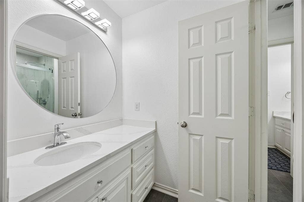 2865 Ridge View Road, Frisco, TX 75034 White paneled door opening to a vanity area with a chrome faucet, oval sink, and a circular mirror