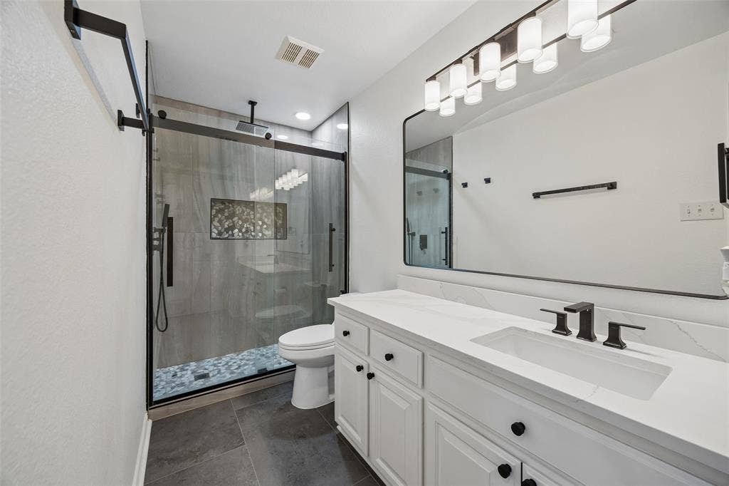 2865 Ridge View Road, Frisco, TX 75034 Spacious bathroom featuring a frameless glass shower, built-in shower niche, floating vanity with an integrated sink, and an expansive mirror