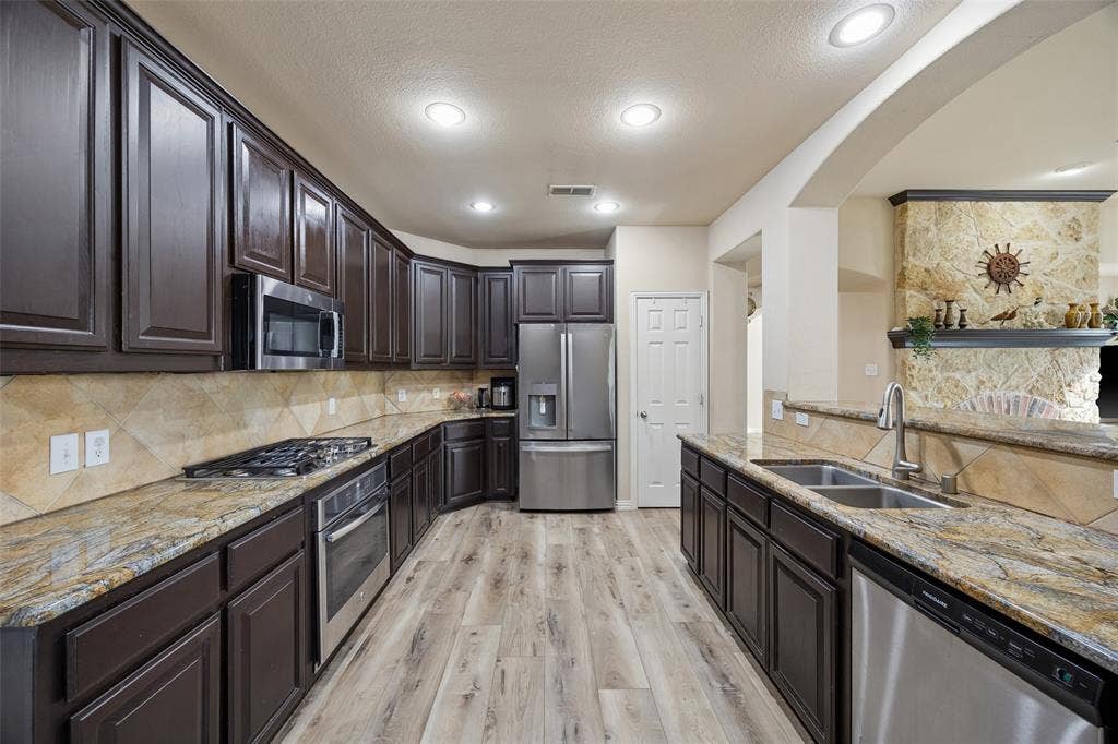 2865 Ridge View Road, Frisco, TX 75034 Kitchen featuring wood-finish flooring, dark wood cabinetry, stainless steel appliances, granite countertops, and recessed lighting