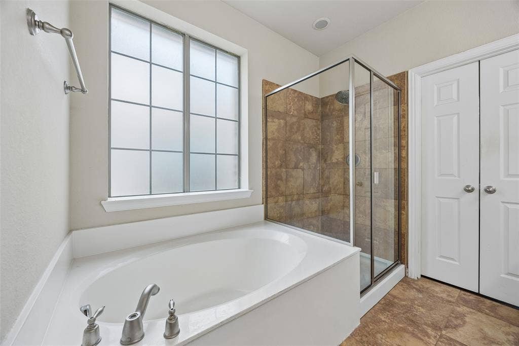 2865 Ridge View Road, Frisco, TX 75034 Built-in soaking tub, glass-enclosed shower with tile surround, privacy window, and wood-finish flooring