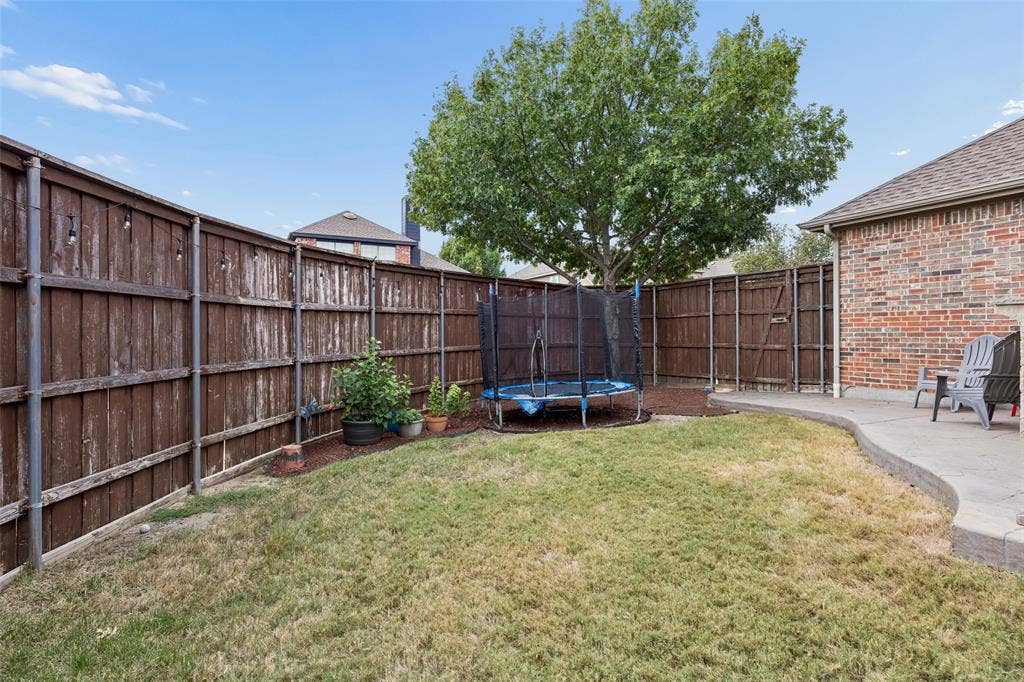 2865 Ridge View Road, Frisco, TX 75034 Private backyard featuring a concrete patio, wood privacy fencing, and a mature tree