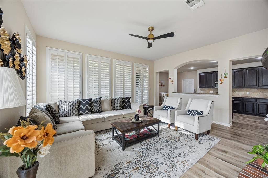 2865 Ridge View Road, Frisco, TX 75034 Spacious living area featuring plank flooring, multiple windows with plantation shutters, and a modern ceiling fan