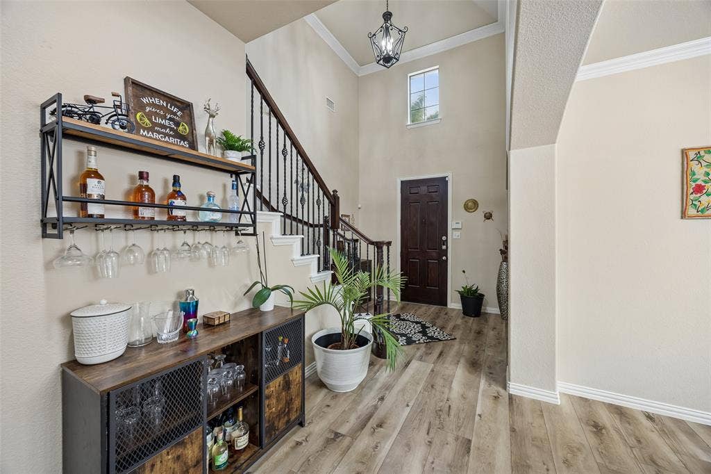 2865 Ridge View Road, Frisco, TX 75034 Two-story foyer with a dark wood-finish entry door, wood-finish flooring, and crown molding