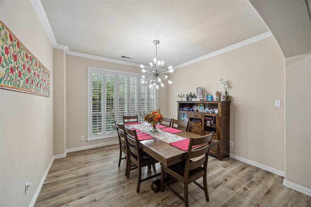 2865 Ridge View Road, Frisco, TX 75034 Wood-finish flooring with crisp white baseboards, crown molding, and a modern chandelier