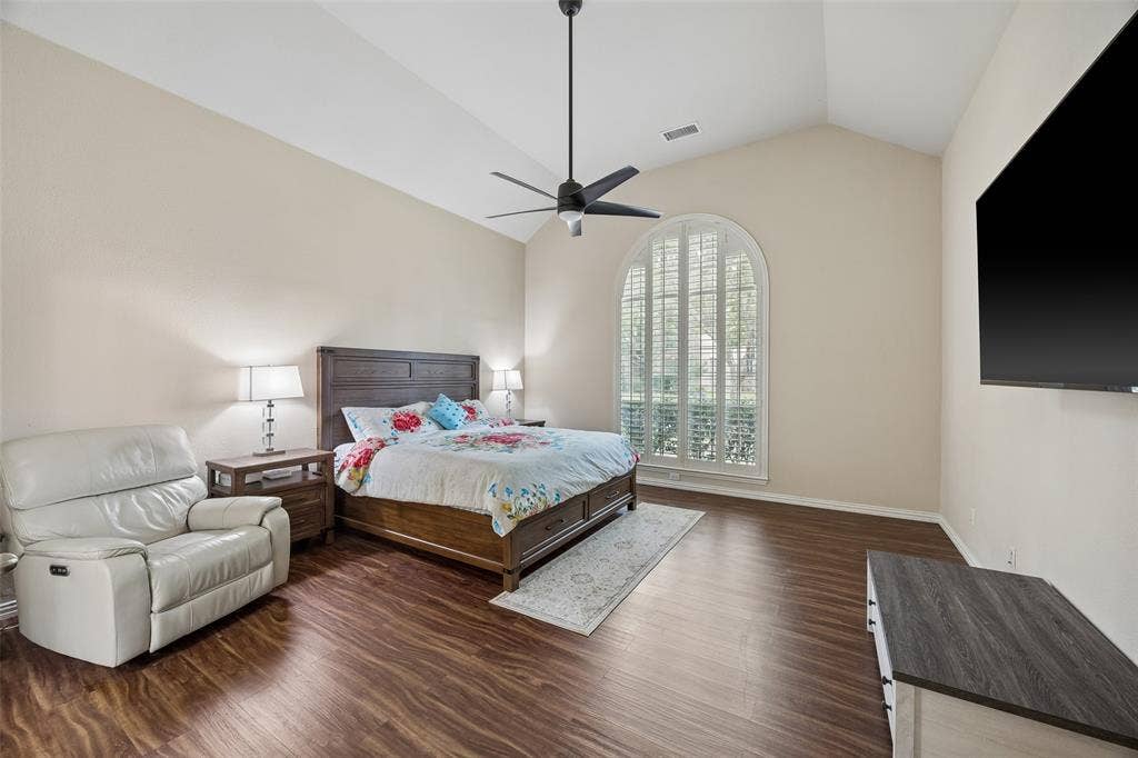 2865 Ridge View Road, Frisco, TX 75034 Vaulted ceiling with a ceiling fan, arched window with plantation shutters, wood-finish flooring, and neutral wall paint