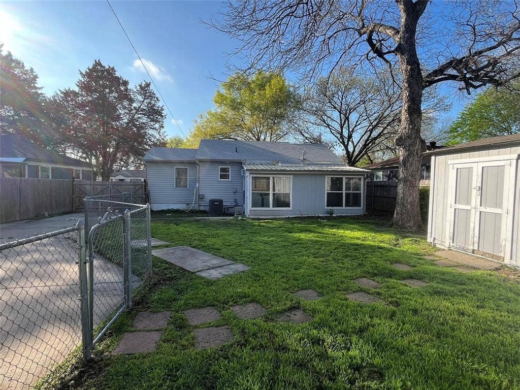 Expansive backyard with a storage shed, established tree, and concrete stepping stones