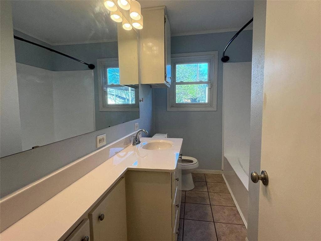 Bathroom featuring a vanity with an integrated sink, polished chrome faucet, full-width mirror, and a window