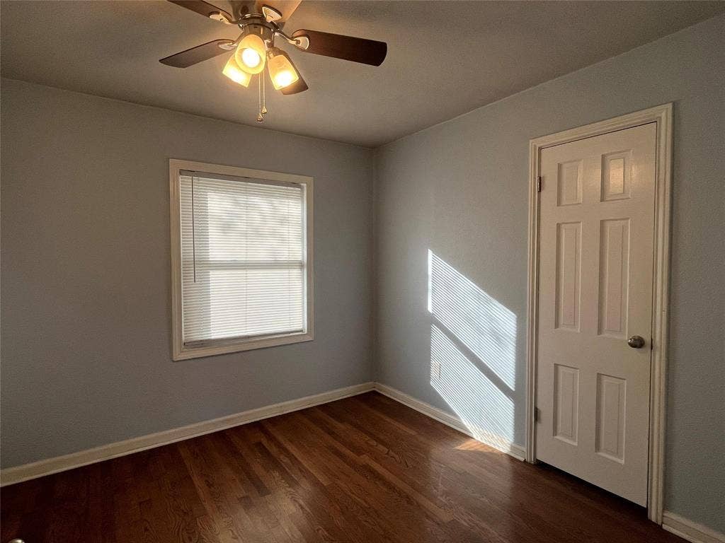 Hardwood flooring, ceiling fan with integrated lighting, paneled door, and window with blinds