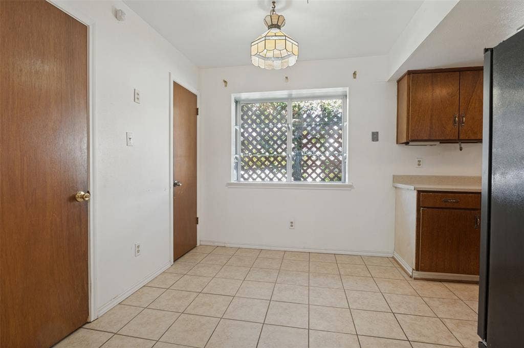 Tile flooring, wood-finish cabinetry, built-in overhead lighting, and a window with lattice detailing