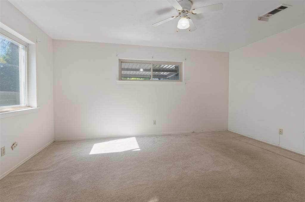 Room featuring two windows, neutral carpeting, a ceiling fan, and white walls