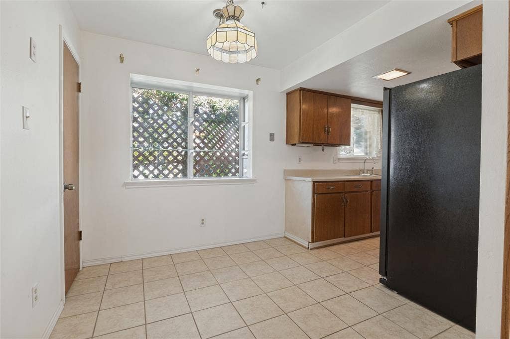 Kitchen dining area featuring tile flooring, a window with lattice work, and an overhead light fixture