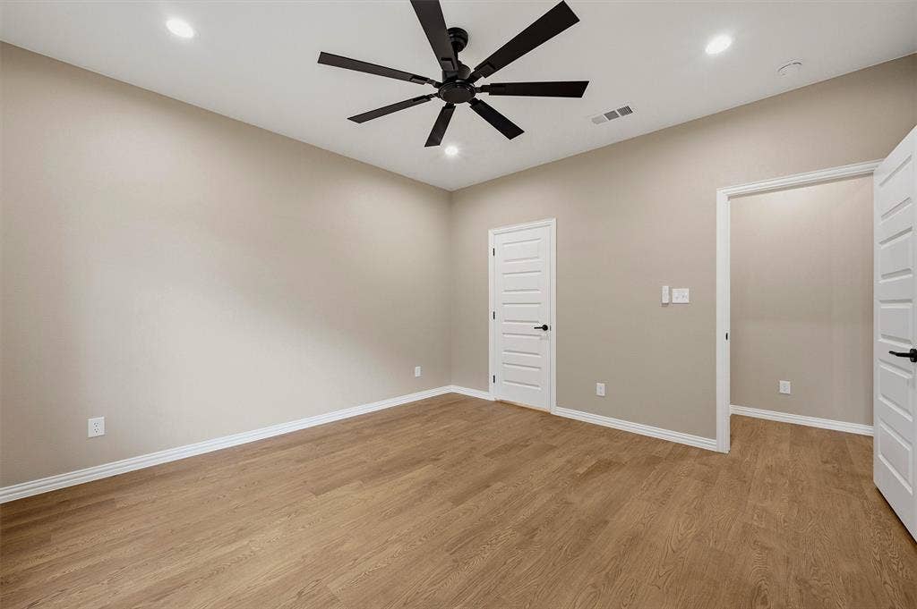 Room featuring wood-finish flooring, a matte black multi-blade ceiling fan, recessed lighting, and white five-panel interior doors with matte black hardware