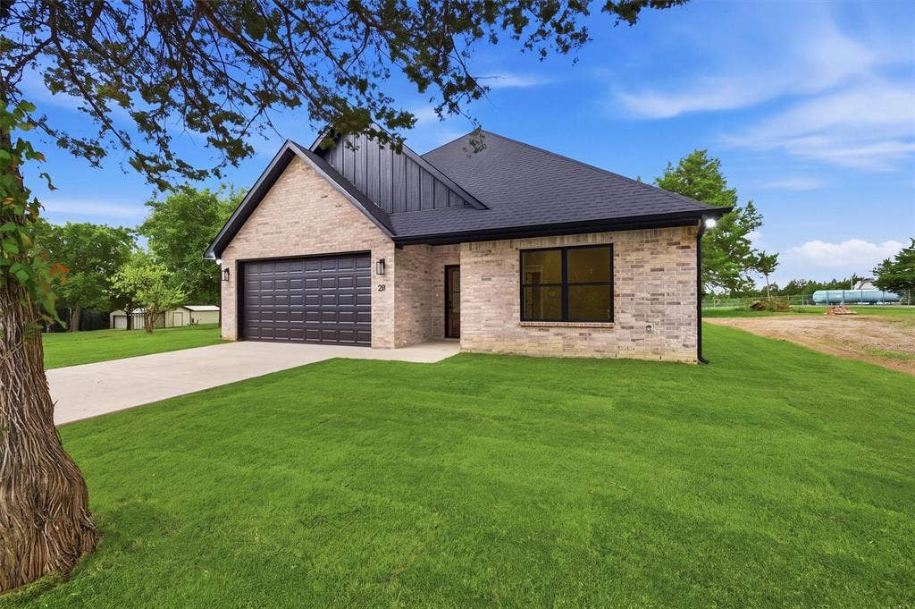 Single-story exterior featuring light-toned masonry, a dark metal roof accent, a multi-car garage, and dark-framed windows